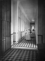 Hôpital Pasteur, couloir du pavillon Roux avec Soeur Godrick au 1er plan passant donner les soins vers 1910-1920